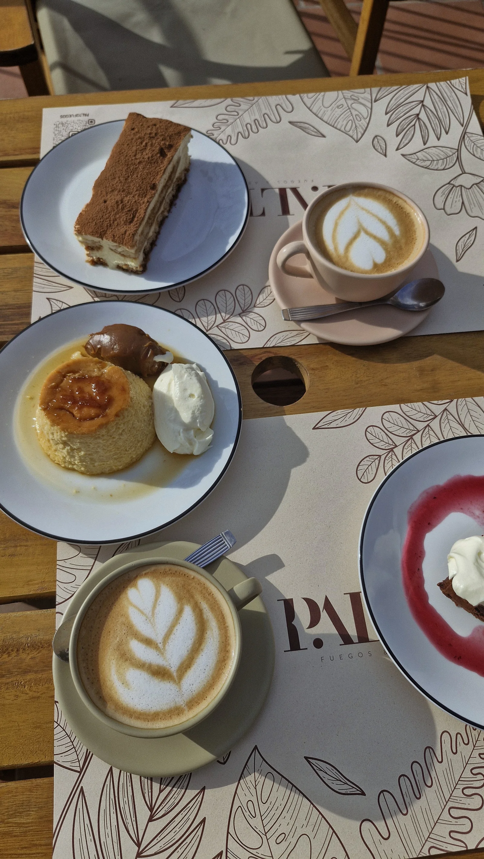 Mesa dulce con café de especialidad, flan casero y torta en el mantel con el line-art de Palto
