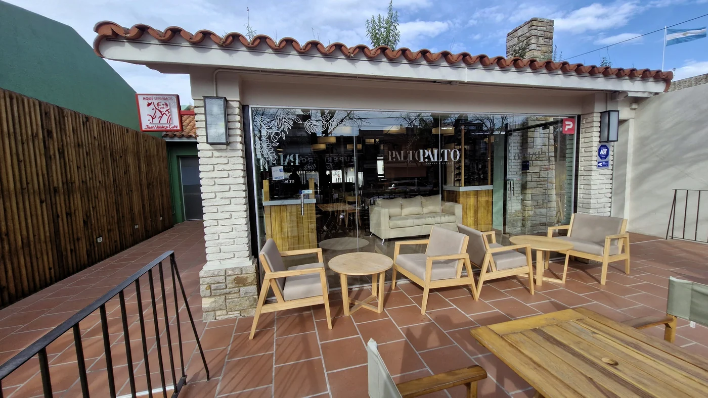 Terraza exterior de Palto con sillones de madera y el ventanal con el logo grabado